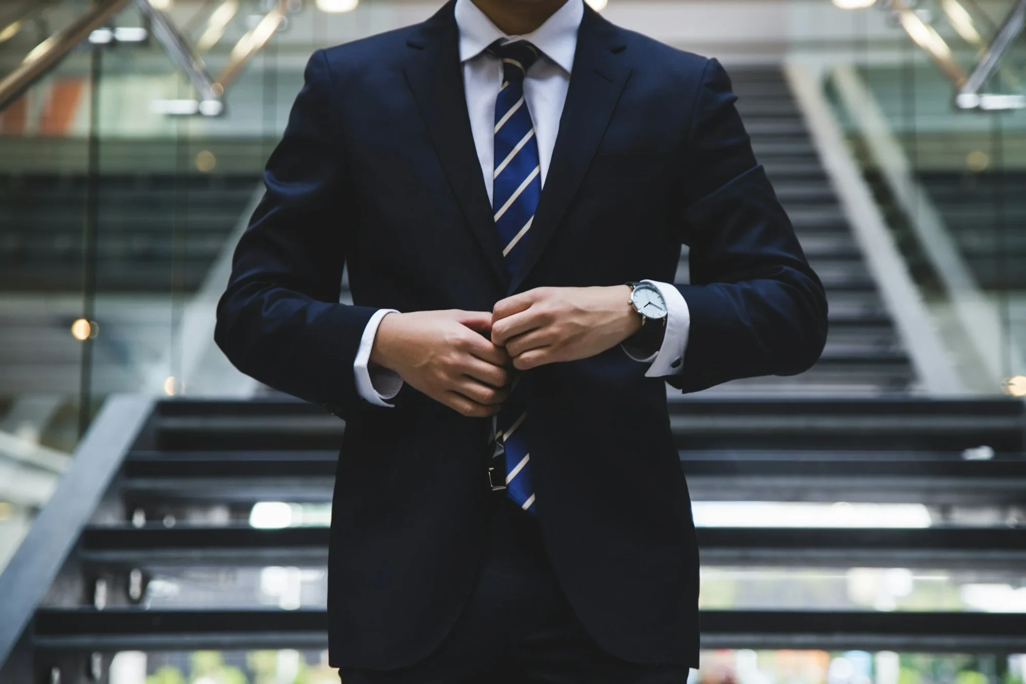 Professional in a navy suit buttoning his jacket
